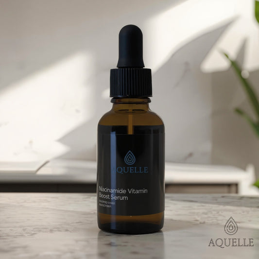 AQUELLE Niacinamide Vitamin Boost Serum in bernsteinfarbener Glasflasche – fotografiert in sanftem Licht mit grünen Pflanzen im Hintergrund, steht für Reinheit und vegane Hautpflege.
